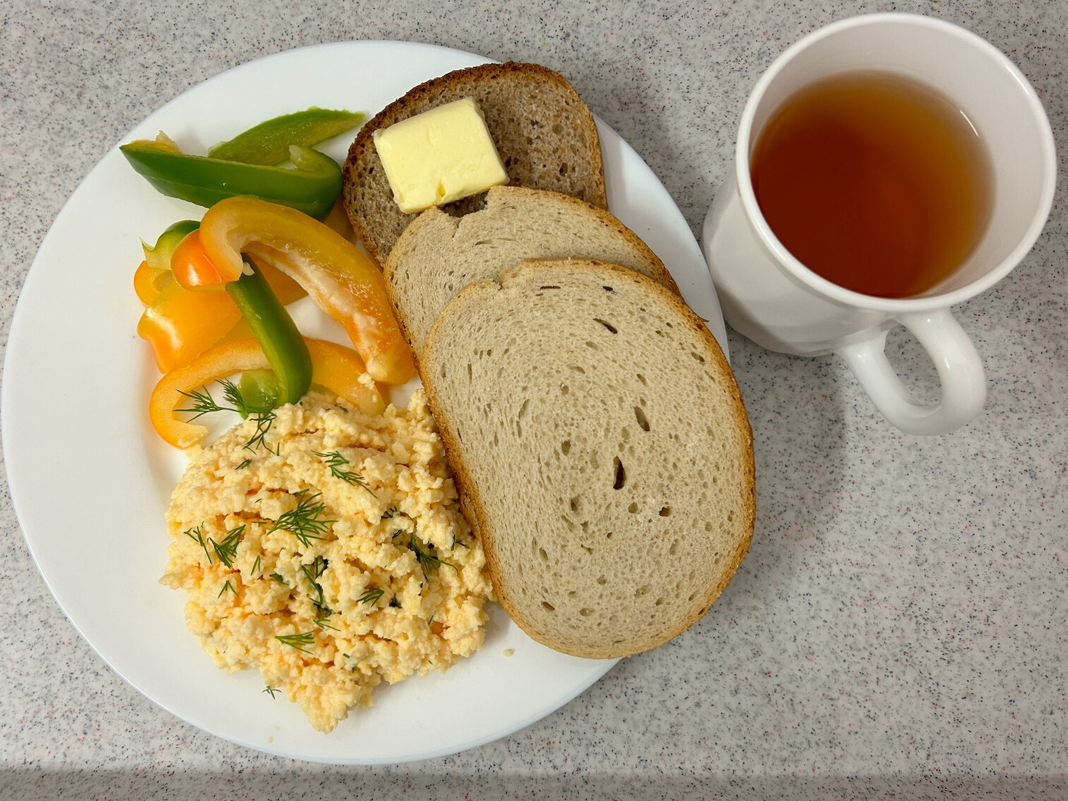 Na zdjęciu znajduje się: Herbata czarna ekspresowa z cytryną Cateringowa, Chleb mieszany pszenno-żytni, Chleb graham, Masło extra 82% , Pasta z jaj z koperkiem, Papryka świeża